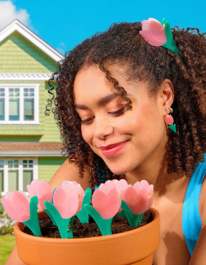 Mise en situation de la Pince à cheveux crabe de la marque Coucou Suzette en acétate de cellulose brillant. L'accessoire prend la forme d'une tulipe graphique de couleur rose avec des feuilles vert tendre.