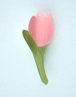 Pince à cheveux crabe de la marque Coucou Suzette en acétate de cellulose brillant. L'accessoire prend la forme d'une tulipe graphique de couleur rose avec des feuilles vert tendre.