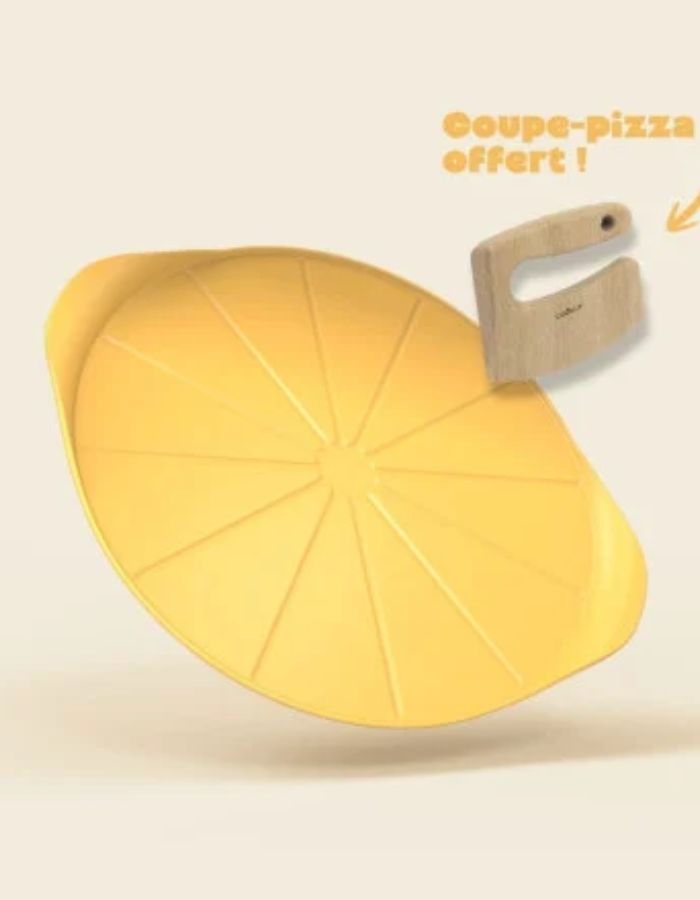 Le Formidable Plat à Pizza Cookut de 33 cm de diamètre, coloris jaune mangue. Plat de cuisson pour le four ultra-léger en métal recyclé avec revêtement antiadhérent, accompagné de son coupe-pizza en bois de hêtre.