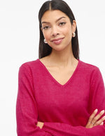 Gros plan sur le Pull en maille fine pour femme modèle Viril de la marque Vila. Coupe droite avec un col en V élégant et des manches longues aux poignets côtelés, couleur rose fuchsia uni et lumineux.