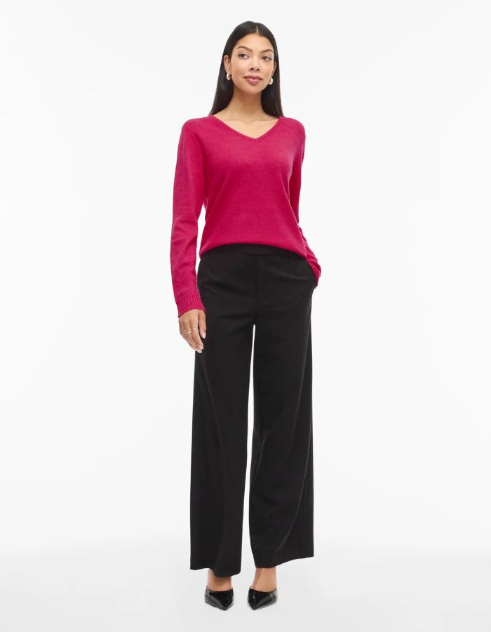 Silhouette avec le Pull en maille fine pour femme modèle Viril de la marque Vila. Coupe droite avec un col en V élégant et des manches longues aux poignets côtelés, couleur rose fuchsia uni et lumineux.