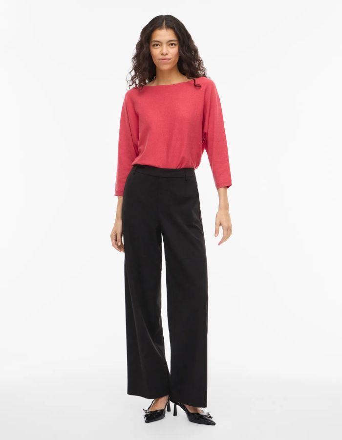 Femme portant un pull Malu col bateau ample couleur Hibiscus avec manches 3/4 et pantalon noir.