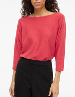 Pull Hibiscus Malu Vila en maille rouge, col bateau, manches 3/4 amples, porté sur un pantalon noir.
