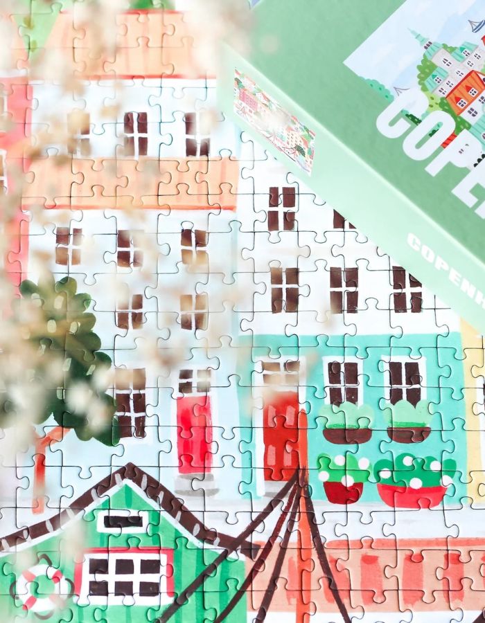 Détail du Puzzle de 1000 pièces pour adulte illustré par Serena White pour Piecely, représentant les canaux et les façades colorées de Copenhague au crépuscule. Présenté à côté de sa boîte de rangement élégante et écoresponsable.