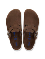 Dessus des Sabots fermés modèle Boston de la marque Birkenstock en cuir velours souple de couleur marron foncé Carafe. Présente une bride ajustable à boucle métallique sur le dessus et une semelle anatomique ton sur ton en liège avec lit de pied souple, version chaussant étroit.