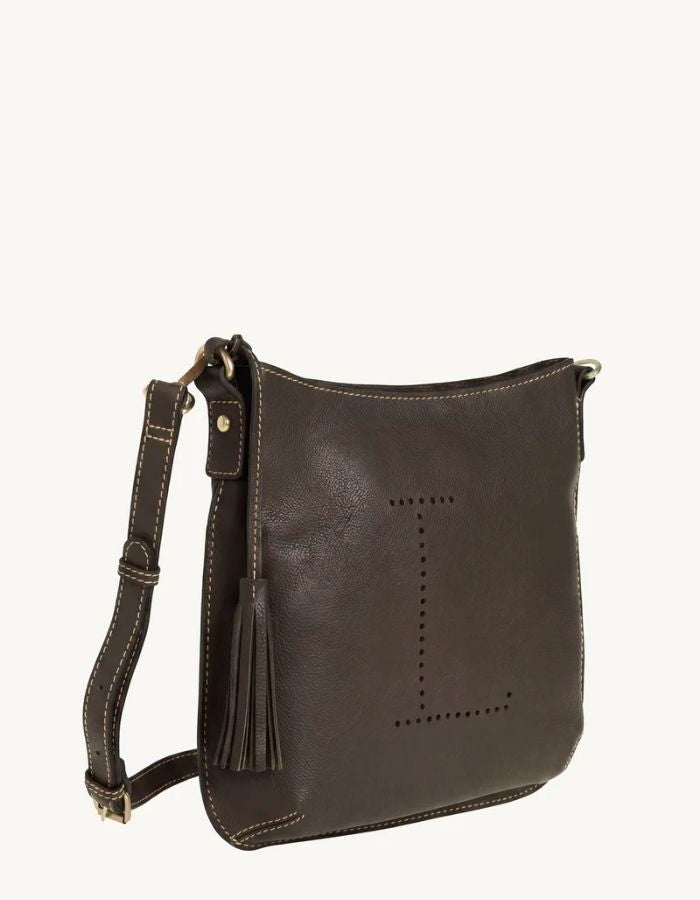 Profil du Sac besace pour femme en cuir grainé marron coffee avec logo L micro-perforé, pompon assorti et bandoulière réglable, modèle Celia L de la marque Loxwood.