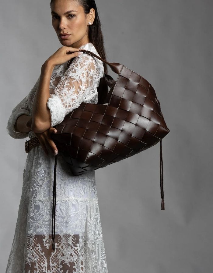 Silhouette portant le Sac cabas pour femme en cuir tressé main marron foncé dark brown à larges brides diagonales avec doublure amovible, modèle Castello de la marque Dragon Diffusion