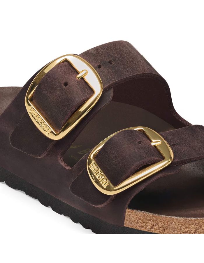 Boucle des Sandales Birkenstock modèle Arizona Big Buckle avec chaussant étroit. Présente deux larges brides en cuir huilé épais à bords bruts dotées de grandes boucles métalliques élégantes, montées sur la célèbre semelle anatomique en liège et cuir lisse assorti.