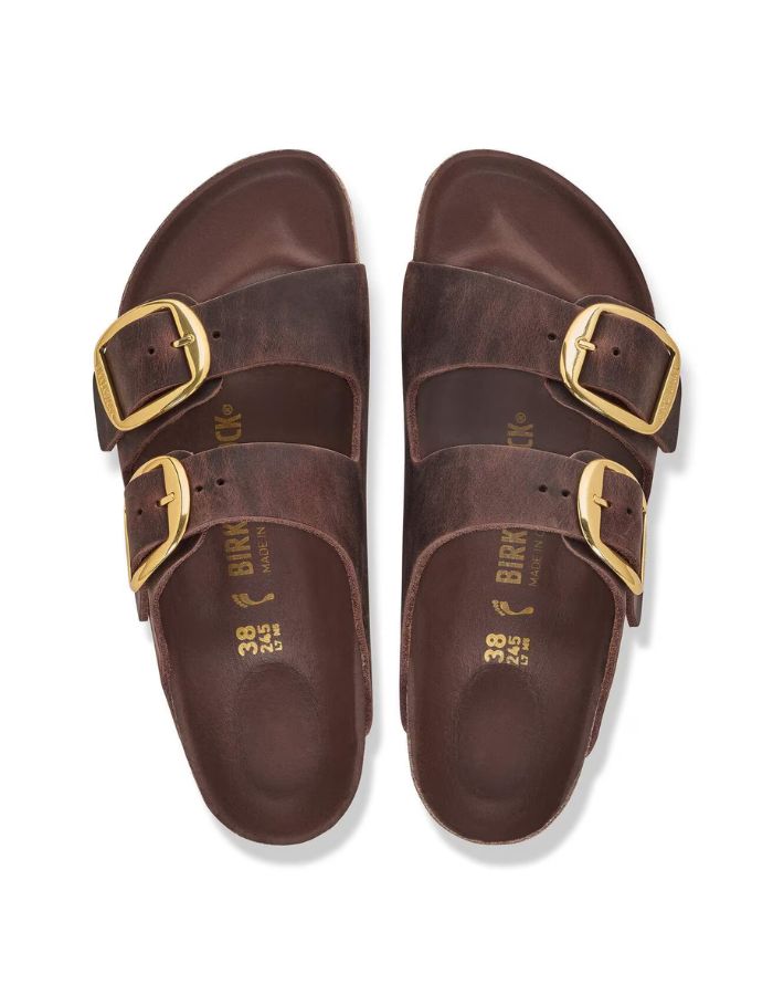 dessus des Sandales Birkenstock modèle Arizona Big Buckle avec chaussant étroit. Présente deux larges brides en cuir huilé épais à bords bruts dotées de grandes boucles métalliques élégantes, montées sur la célèbre semelle anatomique en liège et cuir lisse assorti.