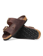 Semelle des Sandales Birkenstock modèle Arizona Big Buckle avec chaussant étroit. Présente deux larges brides en cuir huilé épais à bords bruts dotées de grandes boucles métalliques élégantes, montées sur la célèbre semelle anatomique en liège et cuir lisse assorti.