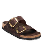 Sandales Birkenstock modèle Arizona Big Buckle avec chaussant étroit. Présente deux larges brides en cuir huilé épais à bords bruts dotées de grandes boucles métalliques élégantes, montées sur la célèbre semelle anatomique en liège et cuir lisse assorti.