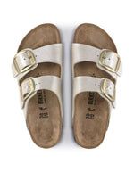 Paire de Sandales Birkenstock Arizona Big Buckle en largeur étroite. Les deux brides réglables sont en Birko-Flor® blanc nacré satiné (Graceful Pearl White) avec de grandes boucles en métal argenté, reposant sur une semelle anatomique en liège et cuir velours.