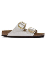 Profil des Sandales Birkenstock Arizona Big Buckle en largeur étroite. Les deux brides réglables sont en Birko-Flor® blanc nacré satiné (Graceful Pearl White) avec de grandes boucles en métal argenté, reposant sur une semelle anatomique en liège et cuir velours.