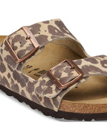 Boucle des Sandales d'été pour femme modèle Arizona de la marque Birkenstock, en cuir velours à imprimé léopard Leo Sandcastle beige et marron. Présentent deux brides larges réglables avec des boucles en métal noir et la célèbre semelle anatomique en liège naturel.