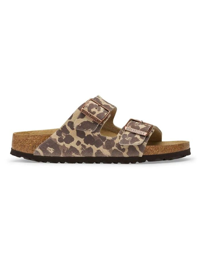 Profil des Sandales d'été pour femme modèle Arizona de la marque Birkenstock, en cuir velours à imprimé léopard Leo Sandcastle beige et marron. Présentent deux brides larges réglables avec des boucles en métal noir et la célèbre semelle anatomique en liège naturel.