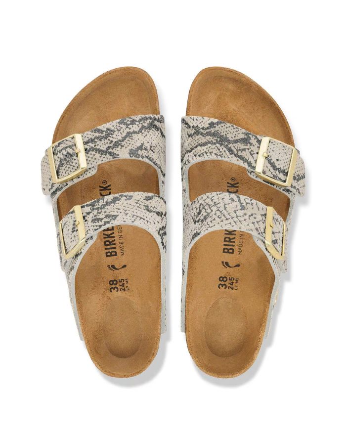 Dessus des Sandales pour pieds fins en largeur Narrow, modèle emblématique Arizona Rivet Logo de la marque Birkenstock. Confectionnées en cuir velours souple de couleur claire beige huître Snake Oyster, elles présentent deux brides horizontales ajustables avec boucles en métal, un rivet logo et la célèbre semelle anatomique marron en liège naturel