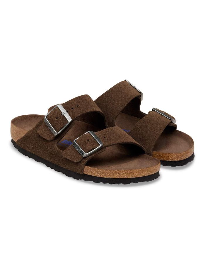 Paire de Sandales Birkenstock modèle Arizona avec chaussant étroit. Présente deux brides ajustables en cuir velours souple de couleur marron foncé Carafe avec des boucles en métal assorties, montées sur la célèbre semelle anatomique en liège avec lit de pied souple.