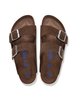 Dessus des Sandales Birkenstock modèle Arizona avec chaussant étroit. Présente deux brides ajustables en cuir velours souple de couleur marron foncé Carafe avec des boucles en métal assorties, montées sur la célèbre semelle anatomique en liège avec lit de pied souple.