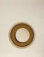 Mise en situation du Set de table rond Globe par Maison Sarah Lavoine, confectionné en raphia naturel tressé à la main. Centre de couleur jaune Safran vibrant et bordure contrastée en coloris naturel. Design artisanal fabriqué à Madagascar, diamètre 38 cm.