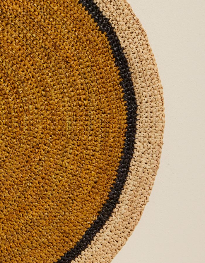 Détail du Set de table rond Globe par Maison Sarah Lavoine, confectionné en raphia naturel tressé à la main. Centre de couleur jaune Safran vibrant et bordure contrastée en coloris naturel. Design artisanal fabriqué à Madagascar, diamètre 38 cm.