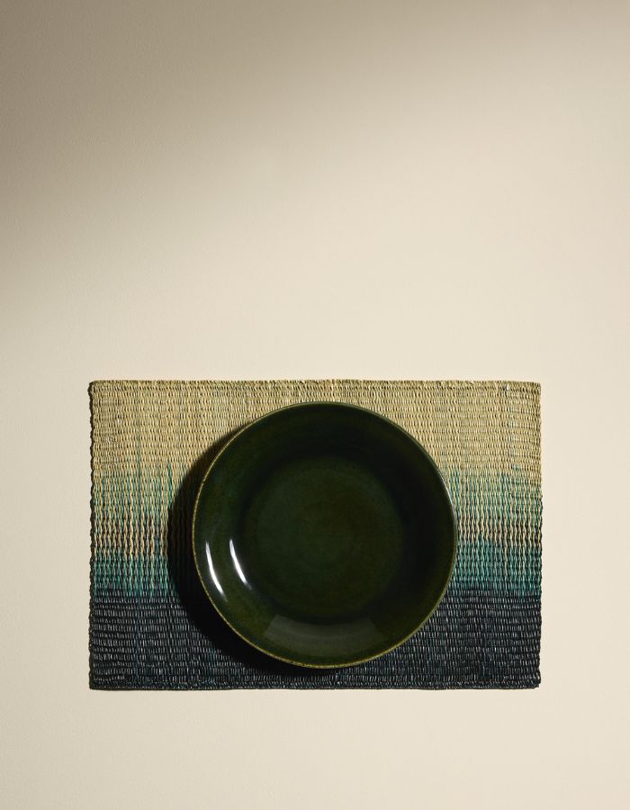 assiette sur un Set de table rectangulaire Orée Forêt par Maison Sarah Lavoine. Tressage artisanal en fibres naturelles de Carex avec dégradé vert forêt évoquant des silhouettes d'arbres, 45 x 30 cm