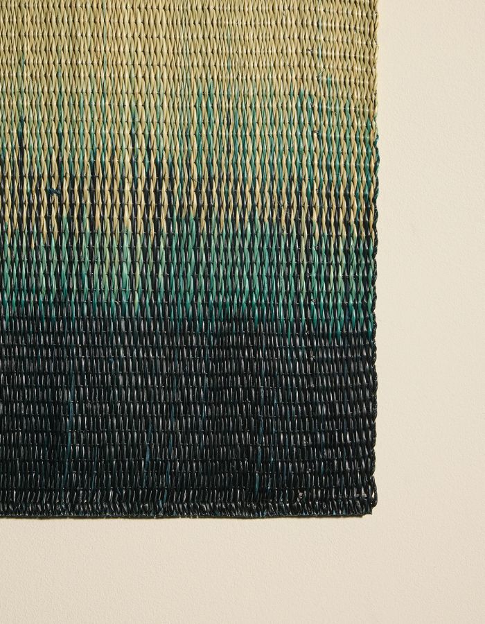 Détail du Set de table rectangulaire Orée Forêt par Maison Sarah Lavoine. Tressage artisanal en fibres naturelles de Carex avec dégradé vert forêt évoquant des silhouettes d'arbres, 45 x 30 cm
