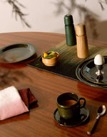 Table avec un Set de table rectangulaire Orée Forêt par Maison Sarah Lavoine. Tressage artisanal en fibres naturelles de Carex avec dégradé vert forêt évoquant des silhouettes d'arbres, 45 x 30 cm