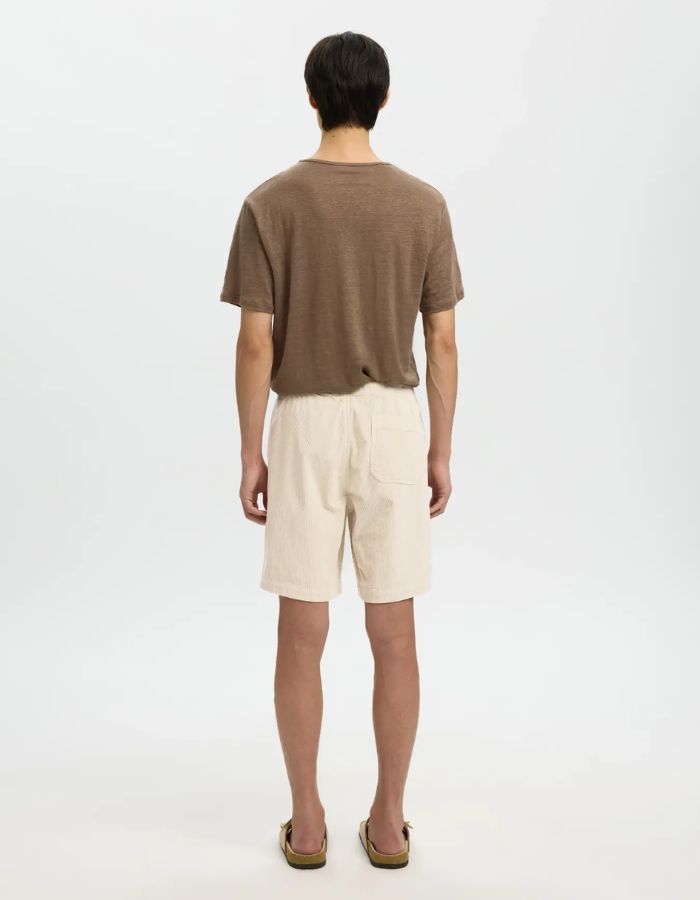 Homme de dos portant un short Ace en velours côtelé beige avec taille élastiquée et poches.