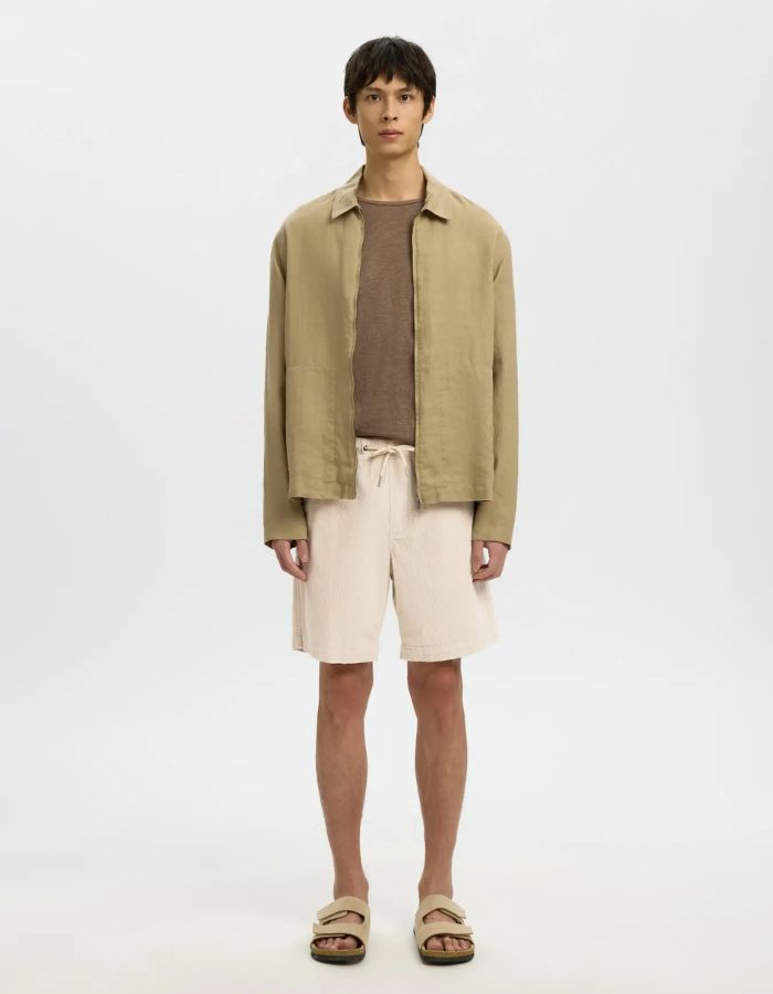 Homme portant un short velours côtelé beige, taille élastiquée avec cordon, longueur au genou.