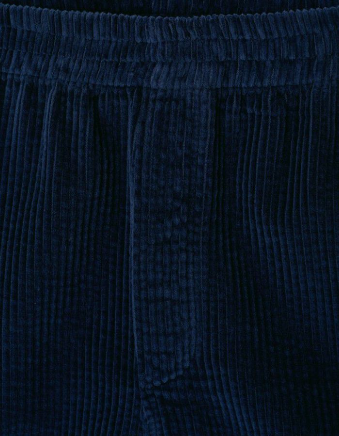 Tissu du Short mi-long pour homme en velours côtelé bleu marine foncé Navy Vintage, modèle Padow de la marque American Vintage. Présente une coupe ample et droite avec une taille élastiquée et des poches discrètes intégrées sur les côtés.
