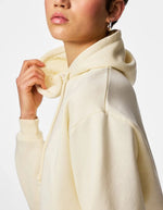 Manche du Sweatshirt à capuche uni pour femme modèle Chilli de la marque Pieces. Coupe droite de couleur blanc cassé grisé White Pepper, doté d'une capuche avec cordons et de manches longues.