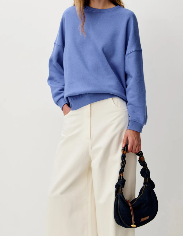 Vue de face du Sweatshirt oversize pour femme en molleton chiné bleu ciel avec col rond boutonné et jacron cuir au dos, modèle Sweat Chebbi couleur Italian Blue de la marque Sessùn.
