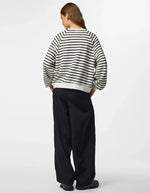 Silhouette de dos avec le Sweatshirt à col rond et manches longues pour femme de couleur écru blanc cassé Cloud Dancer, modèle Greta de la marque PIECES. Présente une coupe classique droite avec un petit cœur noir brodé sur le côté gauche de la poitrine.