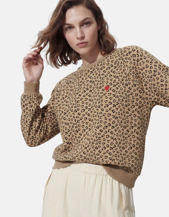 Vue de face du Sweatshirt à col rond et manches longues pour femme avec un imprimé léopard noir et marron sur fond blanc cassé, modèle Greta de la marque PIECES. Présente une broderie rouge vif en forme de cœur sur le côté gauche de la poitrine.