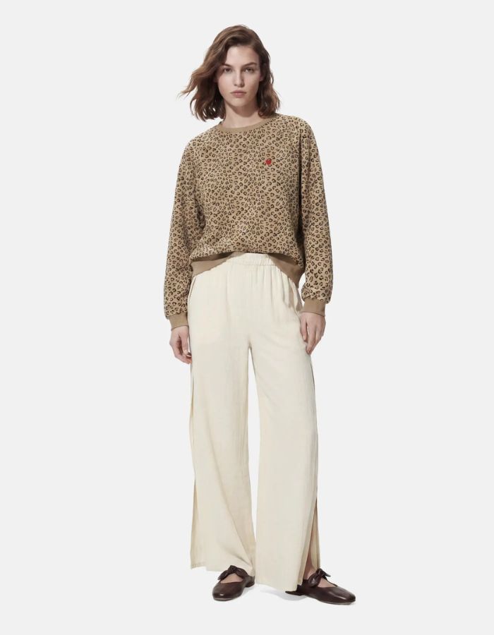 Silhouette avec le Sweatshirt à col rond et manches longues pour femme avec un imprimé léopard noir et marron sur fond blanc cassé, modèle Greta de la marque PIECES. Présente une broderie rouge vif en forme de cœur sur le côté gauche de la poitrine.