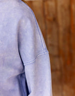 Manche du Sweat-shirt coupe boxy pour femme en molleton parme délavé, modèle Trinkle de la marque LA PETITE ÉTOILE. Présente un col rond, la griffe de la marque sur la poitrine et des finitions en bord-côte.