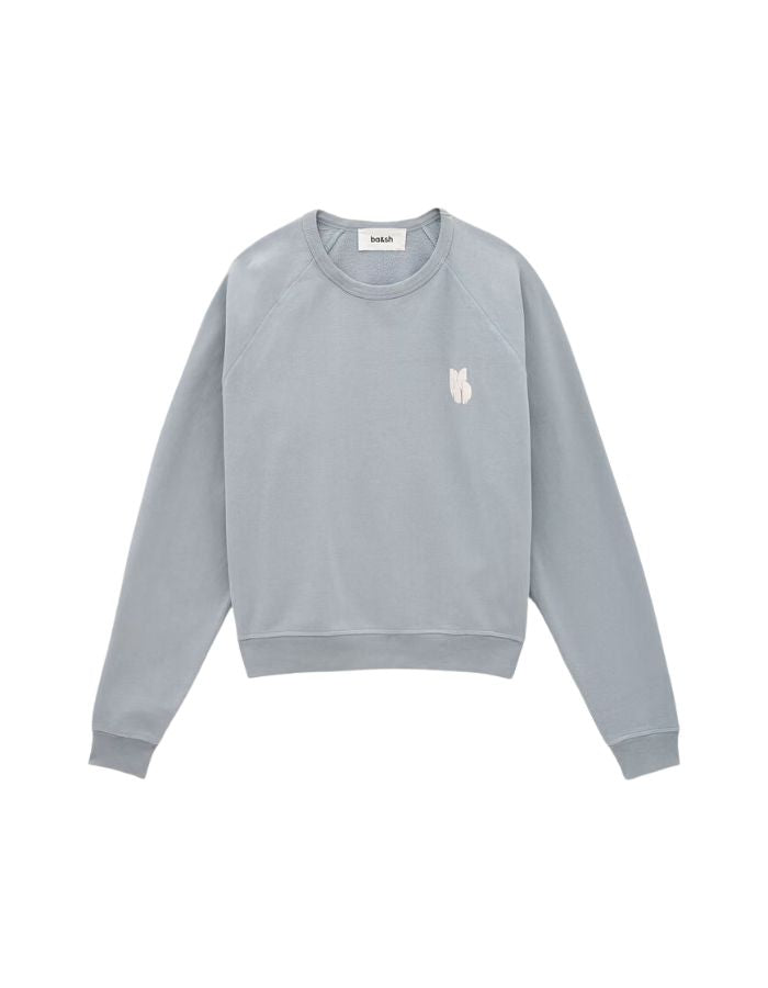 Sweat-shirt pour femme en molleton doux de couleur bleu glacier pastel, modèle Swing de la marque Ba&sh. Présente une coupe ample loose avec col rond et manches raglan, rehaussée de surpiqûres overlock et d'une impression signature Ba&sh texturée sur la poitrine.