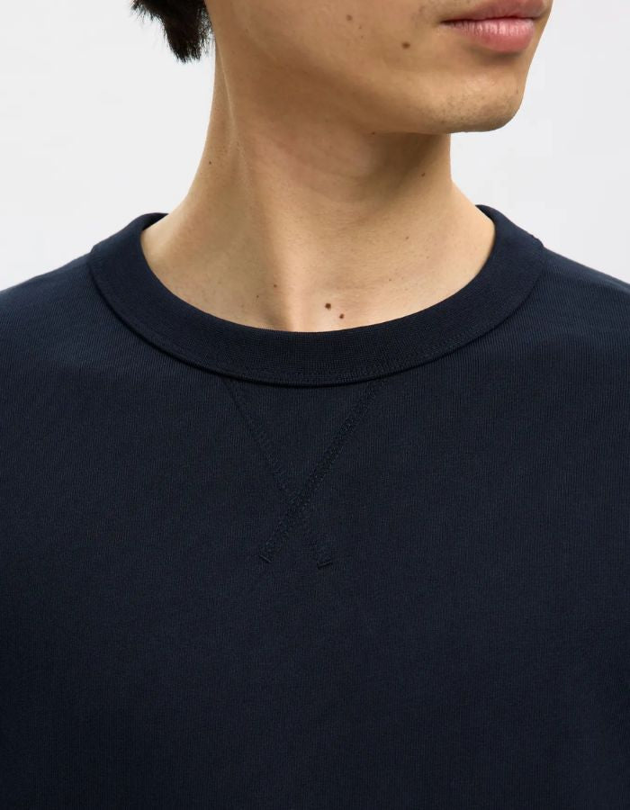 Col du Sweatshirt col rond pour homme en coton biologique bleu marine Navy, modèle Relaxluke de la marque SELECTED HOMME. Présente une coupe droite avec finition en bord-côte au col, aux poignets et à la taille.