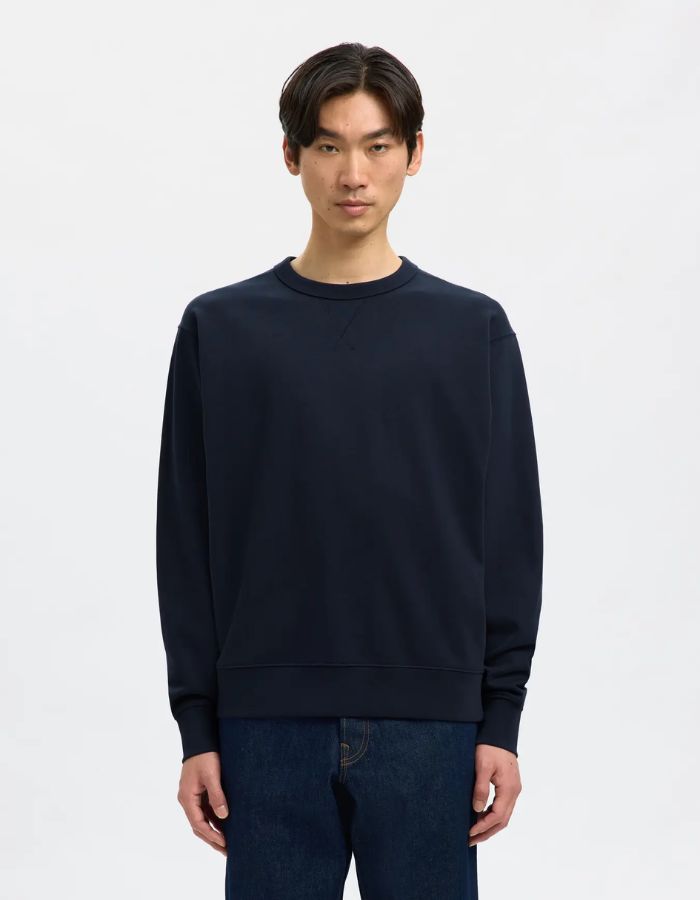 Vue de face du Sweatshirt col rond pour homme en coton biologique bleu marine Navy, modèle Relaxluke de la marque SELECTED HOMME. Présente une coupe droite avec finition en bord-côte au col, aux poignets et à la taille.