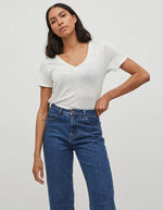 Femme portant un t-shirt blanc col V en jersey et un jean bleu.