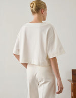 Femme de dos portant un T-Shirt Davina Blanc Cassé en coton organique, coupe droite ample, col bateau, manches courtes larges.