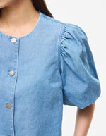 Manche du Top court en jean bleu clair Delila de ROUGE EDIT. Modèle à manches courtes bouffantes, encolure ronde et fermeture par boutons sur le devant. Coupe regular en coton denim.