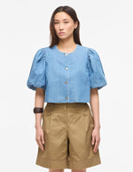 Top court en jean bleu clair Delila de ROUGE EDIT. Modèle à manches courtes bouffantes, encolure ronde et fermeture par boutons sur le devant. Coupe regular en coton denim.