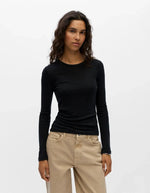 Devant du T-shirt à manches longues pour femme en jersey fluide noir uni, modèle Alma de la marque Object. Présente une coupe droite classique ajustée avec un col rond dégagé, conçu dans une matière douce à l'aspect légèrement satiné.