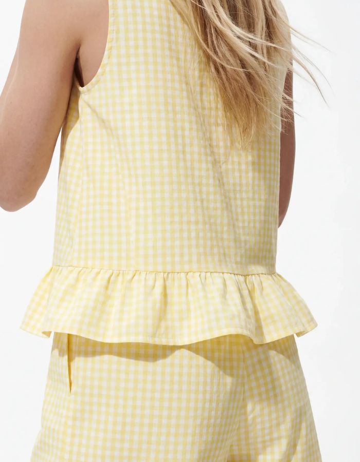 Emmanchure du Top sans manches Bibby de la marque PIECES avec motif Vichy jaune et blanc. Coupe Regular Fit avec découpe à la taille et col rond. Fabriqué en coton biologique et matières recyclées.