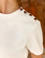 Vue sur l'épaule du T-shirt écru col rond pour femme en coton, modèle Taiga de la marque LA PETITE ÉTOILE. Présente une coupe droite à manches courtes et un boutonnage aspect corne sur l'épaule gauche.