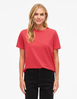 Femme blonde portant un t-shirt rouge corail en jersey de coton biologique à manches courtes et col rond.