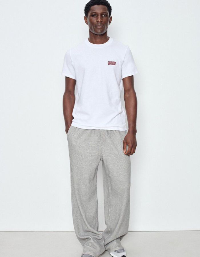 Silhouette avec le T-shirt à manches courtes pour homme de couleur blanc, modèle Ykobow de la marque American Vintage. Présente une coupe droite décontractée en coton doux avec un col rond et le logo American Vintage imprimé dans un style rétro sur la poitrine.