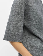 Manche du T-shirt en maille fine pour femme de couleur gris moyen chiné Medium Grey Melange, modèle Denisi de la marque Object. Présente une coupe droite avec col rond classique et des manches mi-longues arrivant au coude, terminées par de larges bords-côtes élastiques.
