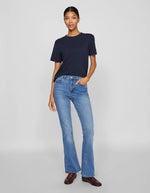 Femme portant un t-shirt navy en coton bio à manches courtes et col rond, avec un jean bleu évasé.